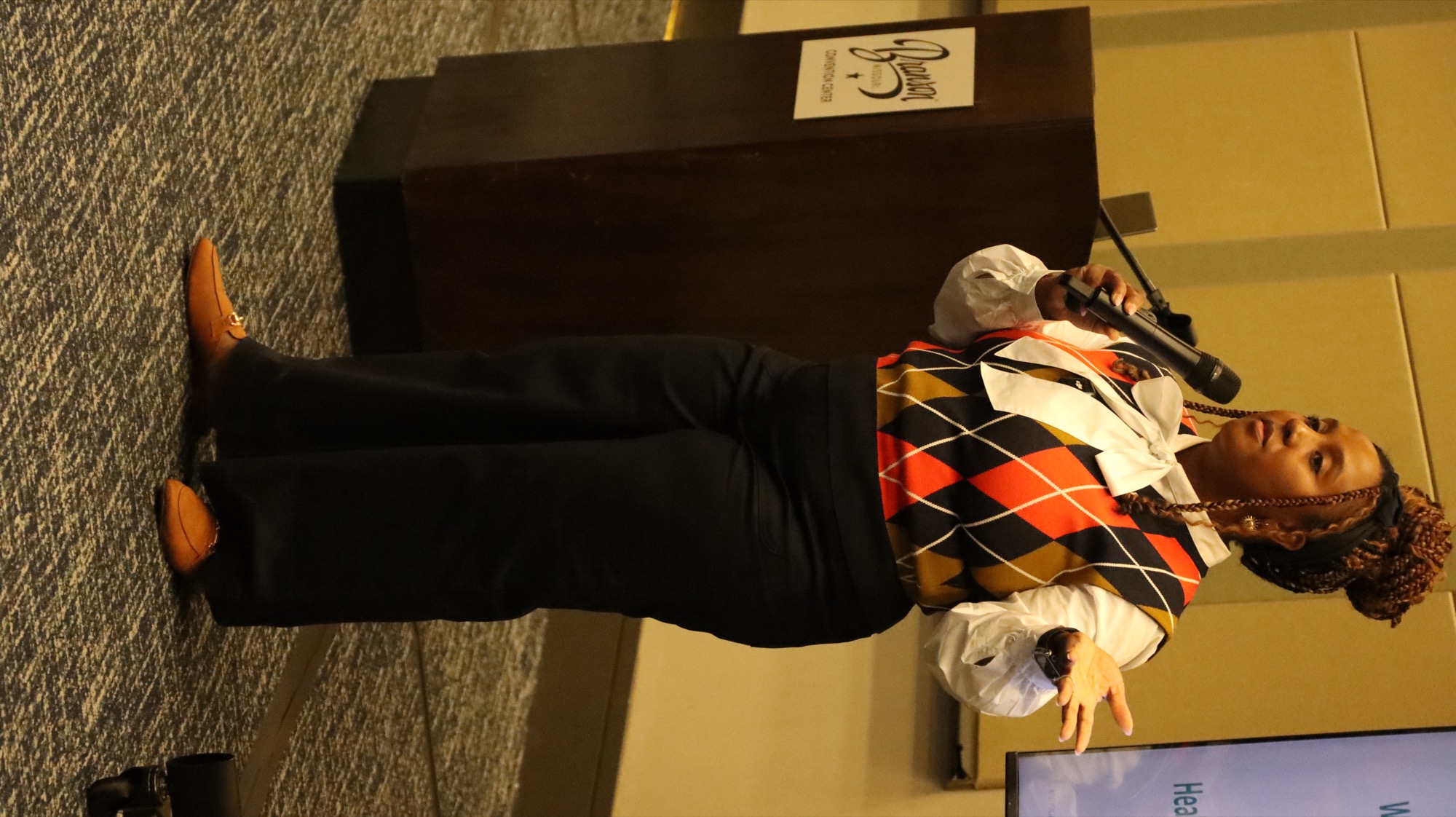 Original event photograph of Shatrasha speaking in her argyle vest
